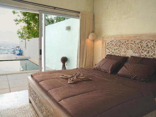 a bedroom with a large bed with a large window at Amada Penida Villa in Nusa Penida