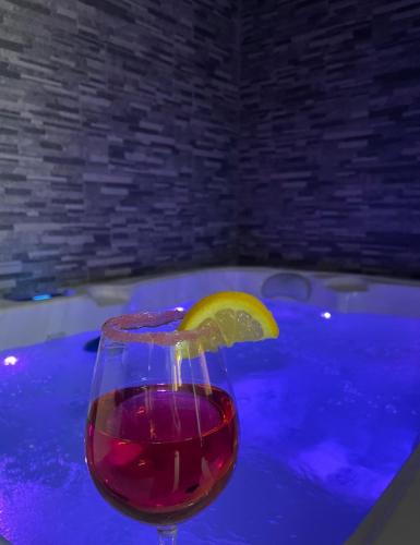 un verre de vin avec un citron vert sur une table à côté d'une baignoire dans l'établissement Apartment with Jacuzzi & Sauna near Toulouse, à Daux