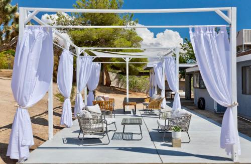 an outdoor marquee with white curtains and chairs at Desert Dream Oasis - Spa, Cabana, Firepit, Disney and Hulu in Yucca Valley