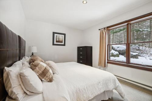 a bedroom with a white bed and a window at Tremblant Naturo-Spa, LAC, PISCINE, TENNIS, GYM in Lac-Superieur