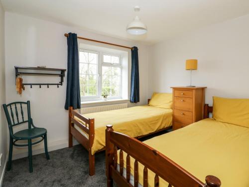 a bedroom with two beds and a chair and a window at 1 Eastview in Louth