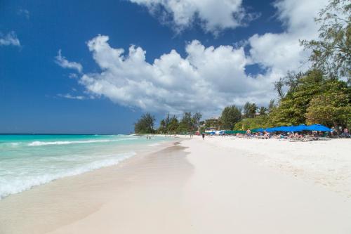 a beach with people sitting on the sand and the ocean at South Beach Hotel Breakfast Incl. - by Ocean Hotels in Bridgetown