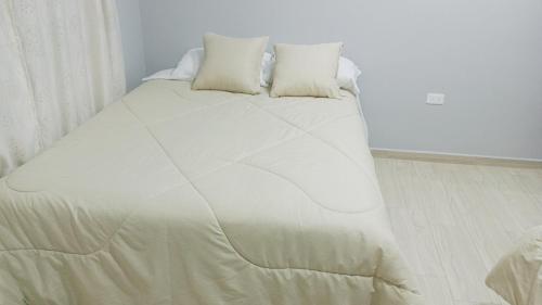 a white bed with two pillows on top of it at Kamel Hause in Baños