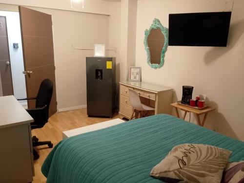 a bedroom with a bed and a desk and a refrigerator at Encantadoras Habitaciones Privadas Del Valle in Mexico City