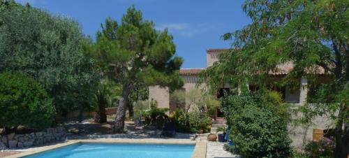 a swimming pool in front of a building with trees at Chez nous Cassis in Cassis