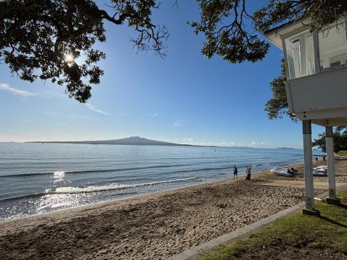 two people standing on a beach near the water at Studio Stay Narrow Neck Beach in Auckland