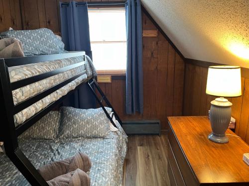 a bedroom with a bunk bed and a table with a lamp at Snow Otter Haus in Bessemer