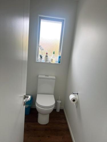 a bathroom with a toilet and a window at Spacious 3 BR house near sumner in Christchurch