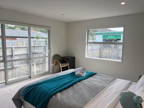 a bedroom with a bed and two windows at Spacious 3 BR house near sumner in Christchurch