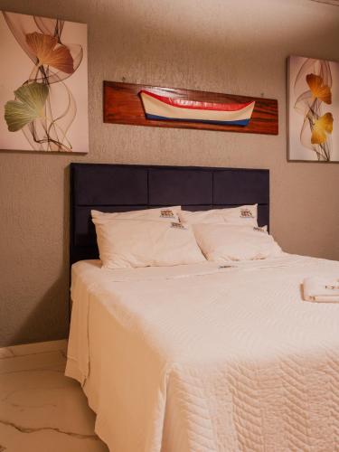 a bedroom with a bed with white sheets and a painting at Pousada Refugio Prumirim in Ubatuba
