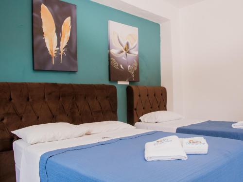 two beds in a room with blue walls and butterflies at Pousada Refugio Prumirim in Ubatuba