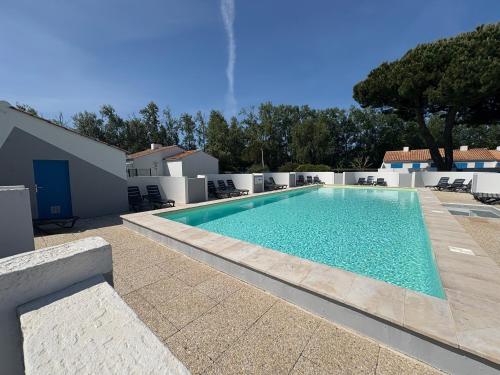 une piscine avec de l'eau bleue dans une cour dans l'établissement Maisonnette studio mezzanine avec piscine chauffée, proche plage et commerces - St Jean de Monts - FR-1-323-269, à Saint-Jean-de-Monts