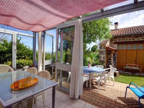 d'une terrasse avec une table, des chaises et des portes en verre. dans l'établissement Gîte de charme à Marols avec jardin, cheminée, wifi et équipements pour toute la famille - FR-1-496-2, à Marols
