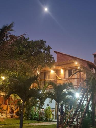 a building with palm trees in front of it at night at Chalés Refúgio Fortim in Fortim