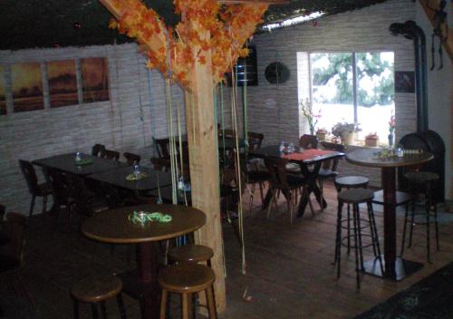 ニデッケンにあるGreen Mile Motelのテーブルと椅子が備わるレストラン、木が並ぶ部屋