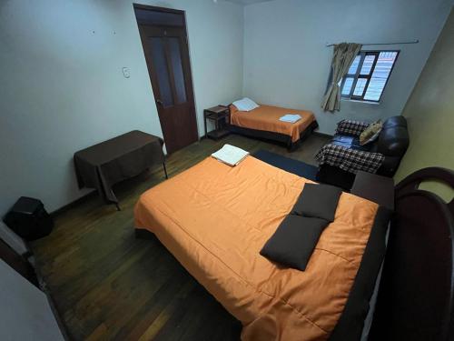 a small bedroom with two beds and a couch at Orkkowasi backpackers in Arequipa