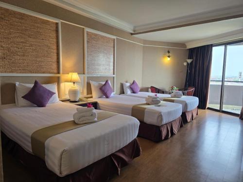 a hotel room with three beds with purple pillows at First Pacific Cirrus in Pattaya Central