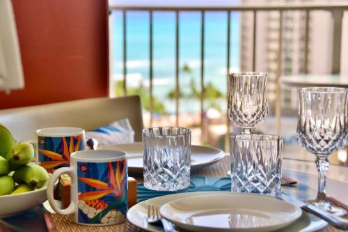 a table with plates and glasses on a table with a view of the ocean at Jenny's Cottage Waikiki in Honolulu