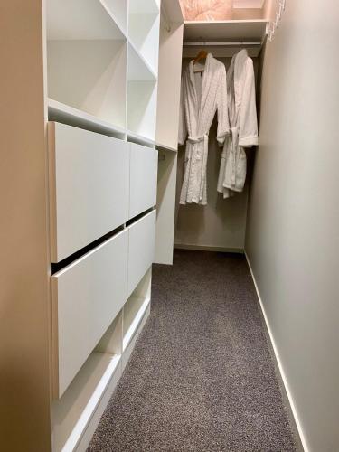 a walk in closet with white cabinets and carpet at Hamurana Lakeview Farmhouse Luxury Retreat in Hamurana