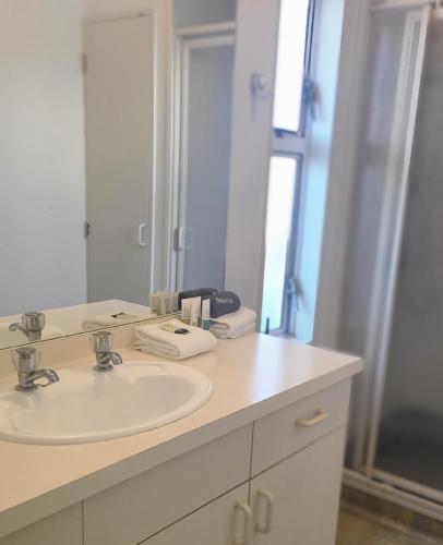 a white bathroom with a sink and a mirror at BK's Fountain Court Motel in Napier