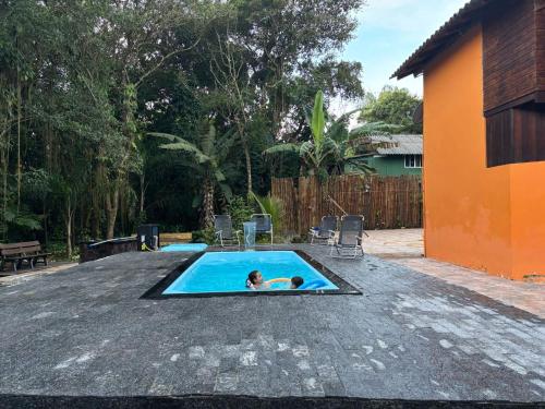 a person swimming in a pool in a backyard at Chalé lawill ilha do mel in Paranaguá
