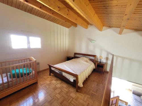 - une chambre avec un lit bébé et un plafond en bois dans l'établissement Maison paisible avec jardin, garage, WiFi, proche plage et commerces - FR-1-92-798, à Les Sables-dʼOlonne