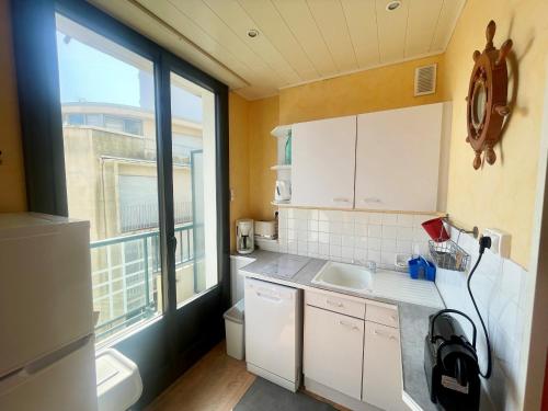 une petite cuisine avec un évier et une fenêtre dans l'établissement T2 Confortable, 2 min de la Plage, Aperçu Mer, Quartier Arago - FR-1-92-572, à Les Sables-dʼOlonne