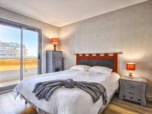 une chambre avec un grand lit et une grande fenêtre dans l'établissement Charmant 2 pièces avec balcon, vue mer et parking - FR-1-788-68, à Cabourg