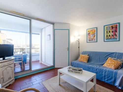 un salon avec un canapé bleu et une télévision dans l'établissement Studio cabine 4 pers avec loggia à Gruissan - FR-1-409-281, à Gruissan