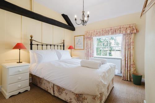 ein Schlafzimmer mit großem Bett und Fenster in der Unterkunft Hicks House - Beautiful Cottage in Leysbourne! in Chipping Campden