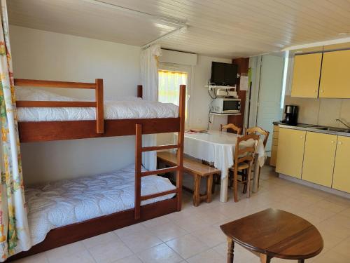 une chambre avec deux lits superposés et une cuisine avec une table dans l'établissement Maisonnette à Barbâtre près plage, 4 pers., terrasse, parking - FR-1-823-156, à Barbâtre