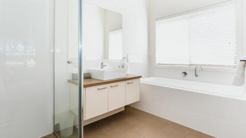 a white bathroom with a sink and a bath tub at Holiday of Perfect Strokes in Cape Schanck