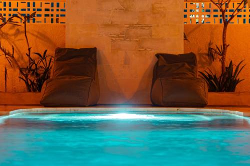 a swimming pool with blue water and two chairs at Kardi Residence By Bali Cabin in Cemagi