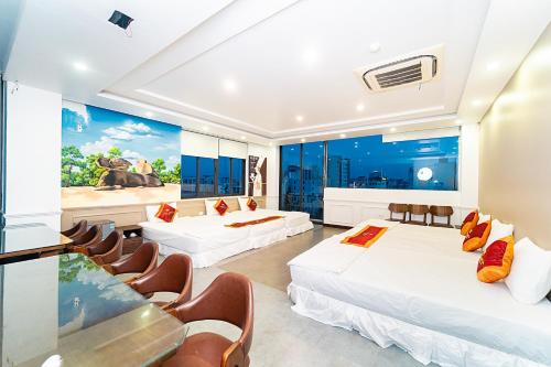 a hotel room with two beds and chairs at MELANTA HOTEL FLC SẦM SƠN in Sầm Sơn