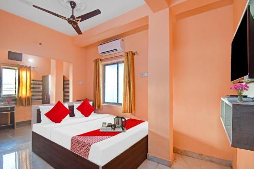 Una habitación con una cama con almohadas rojas y un televisor. en Hotel O Hotel Acronis, en Calcuta