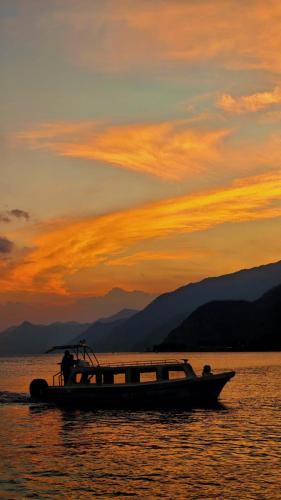a boat in the water with a sunset in the background at Hotel Minnesota y Centro de Eventos Molina in San Lucas Tolimán