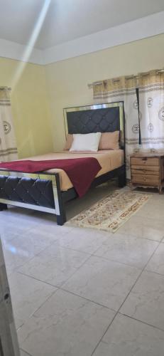 a bedroom with a bed and a dresser at Bella's Cottage in May Pen