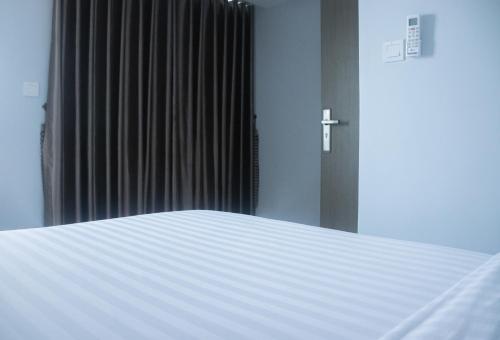 a white bed in a room with a cross on the wall at Parc21 Luxury Boutique Hotel in Phnom Penh