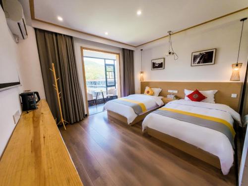 a hotel room with two beds and a balcony at 372 Jingjing's Home Inn in Yongshun