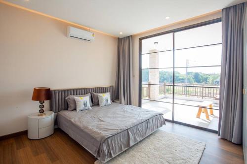 a bedroom with a bed and a large window at Pooler Property in Hua Hin