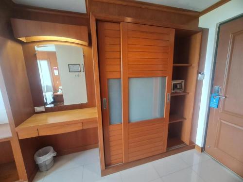 a closet with a wooden door and a mirror at Western Grand Hotel Ratchaburi in Ratchaburi