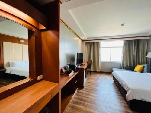 a hotel room with two beds and a mirror at Western Grand Hotel Ratchaburi in Ratchaburi