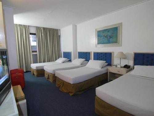una camera d'albergo con tre letti e una televisione di Hotel Supreme a Baguio