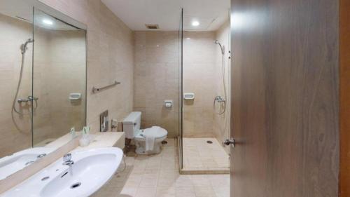 a bathroom with a shower and a sink and a toilet at Grand Cemara Hotel in Jakarta