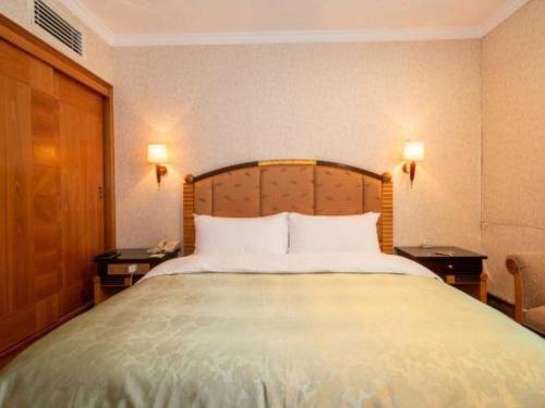 a large bed in a hotel room with two tables at Quanzhou Royal Prince Hotel in Quanzhou