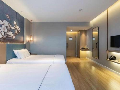 a hotel room with two beds and a flat screen tv at Magnotel Business Jining Huancheng North Road in Jining