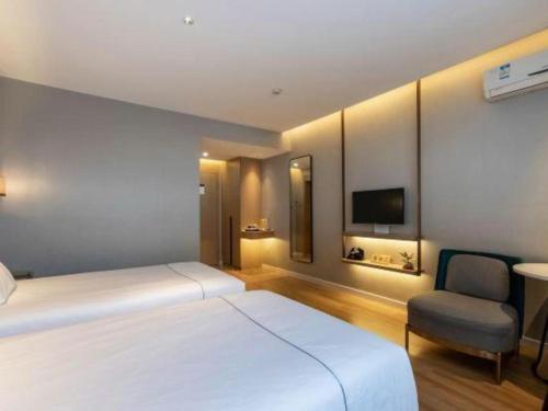a bedroom with a large white bed and a chair at Magnotel Business Jining Huancheng North Road in Jining