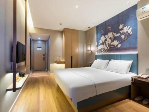 a bedroom with a large bed and a painting on the wall at Magnotel Business Jining Huancheng North Road in Jining