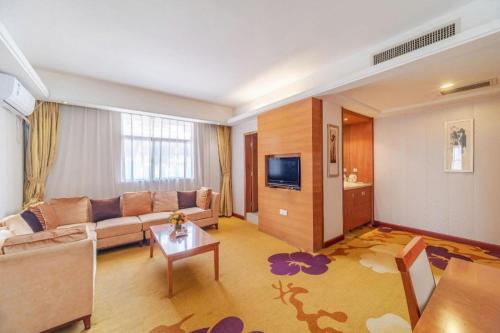 a living room with a couch and a tv at Lijiang Waika Hotel in Lijiang