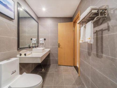 a bathroom with a toilet and a sink and a mirror at Lijiang Waika Hotel in Lijiang